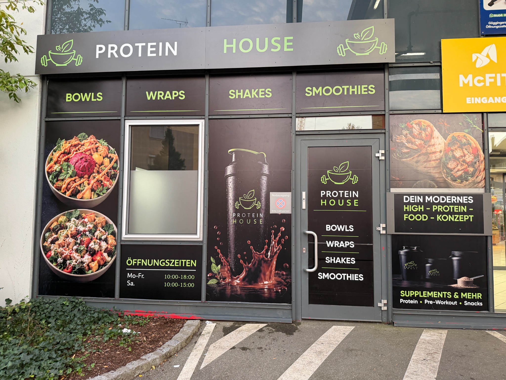 Außenansicht von Protein House Augsburg mit Logo und den Angeboten Bowls, Wraps, Shakes und Smoothies